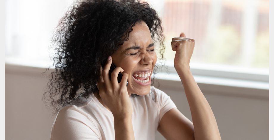 Mujer feliz al teléfono porque recibe ayuda para conseguir empleo.