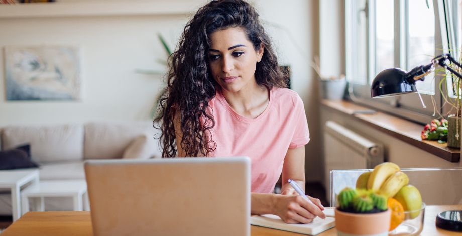 Mujer en frente de su laptop, concentrada en la pantalla.